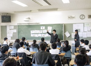 2年生の実演に聞き入る1年生。後でまた勉強できるよう、タブレットで録画する生徒も。KP法とは、紙に説明の要点を書き、それを黒板に貼りながらプレゼンテーションを行う方法です