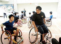 車椅子バスケの選手に車椅子の動かし方を教わる生徒