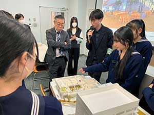 東急建設の設計者から模型解説を受ける生徒たち。